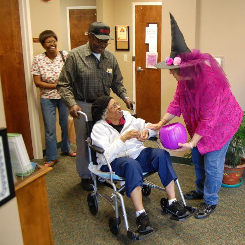 a woman in a witch hat gives candy to a woman in a wheelchair